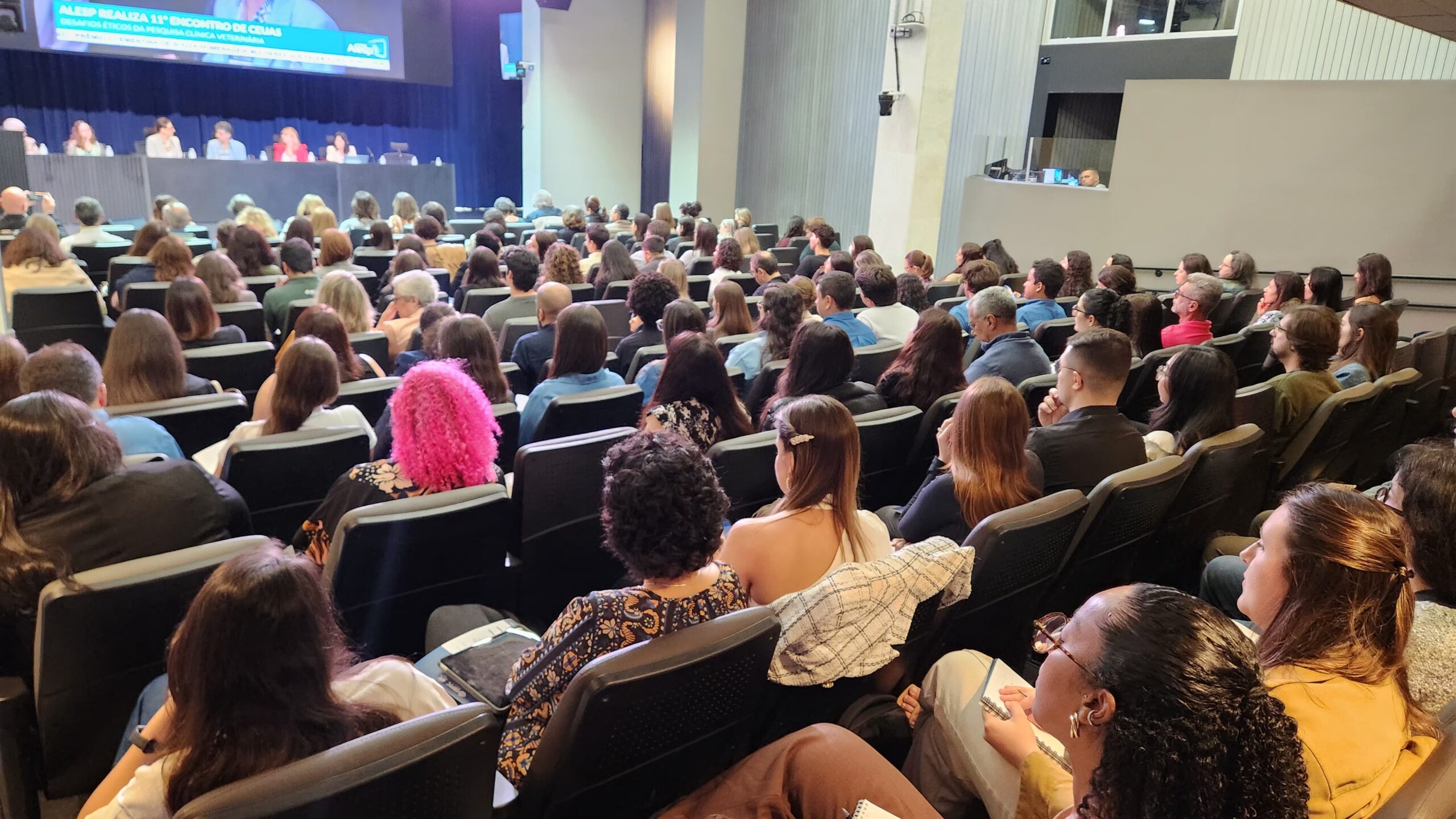 Pessoas sentadas frente ao palco.