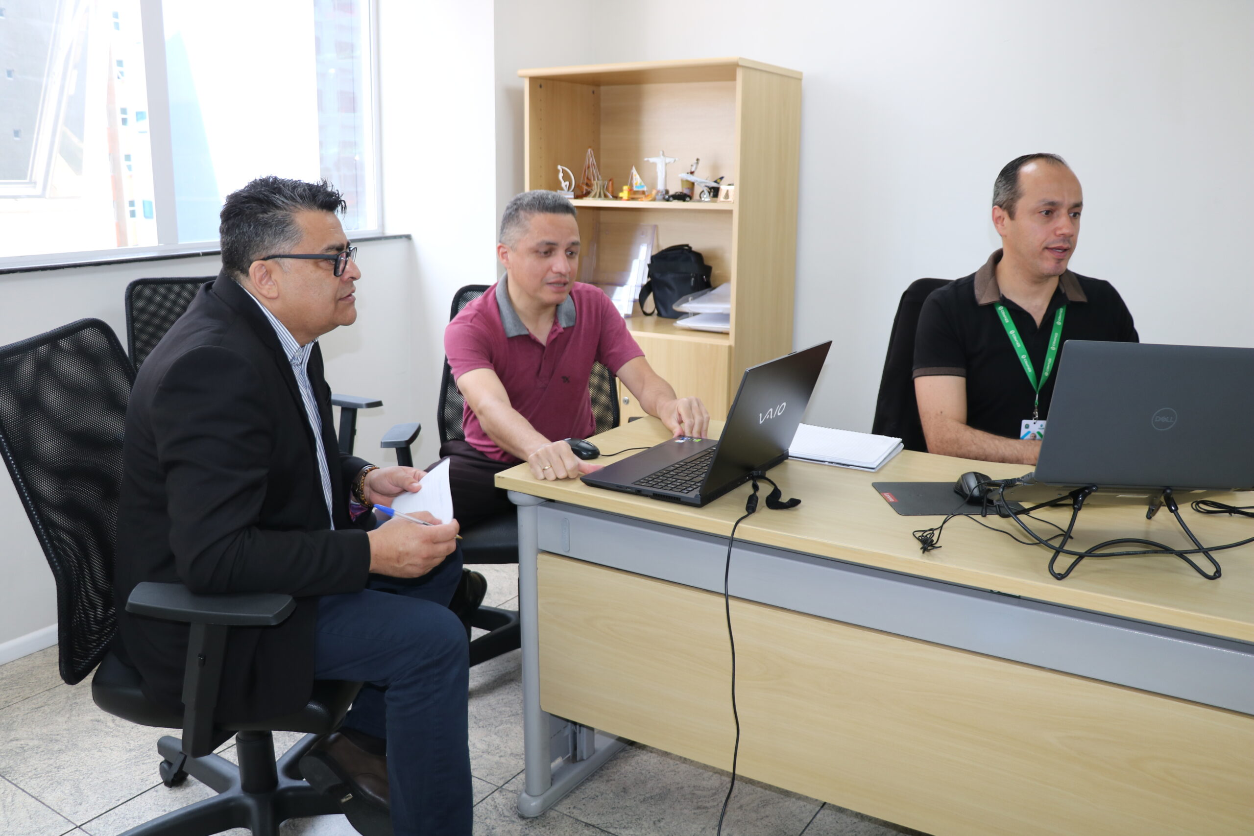 3 pessoas reunidas em uma sala, mexendo em um computador