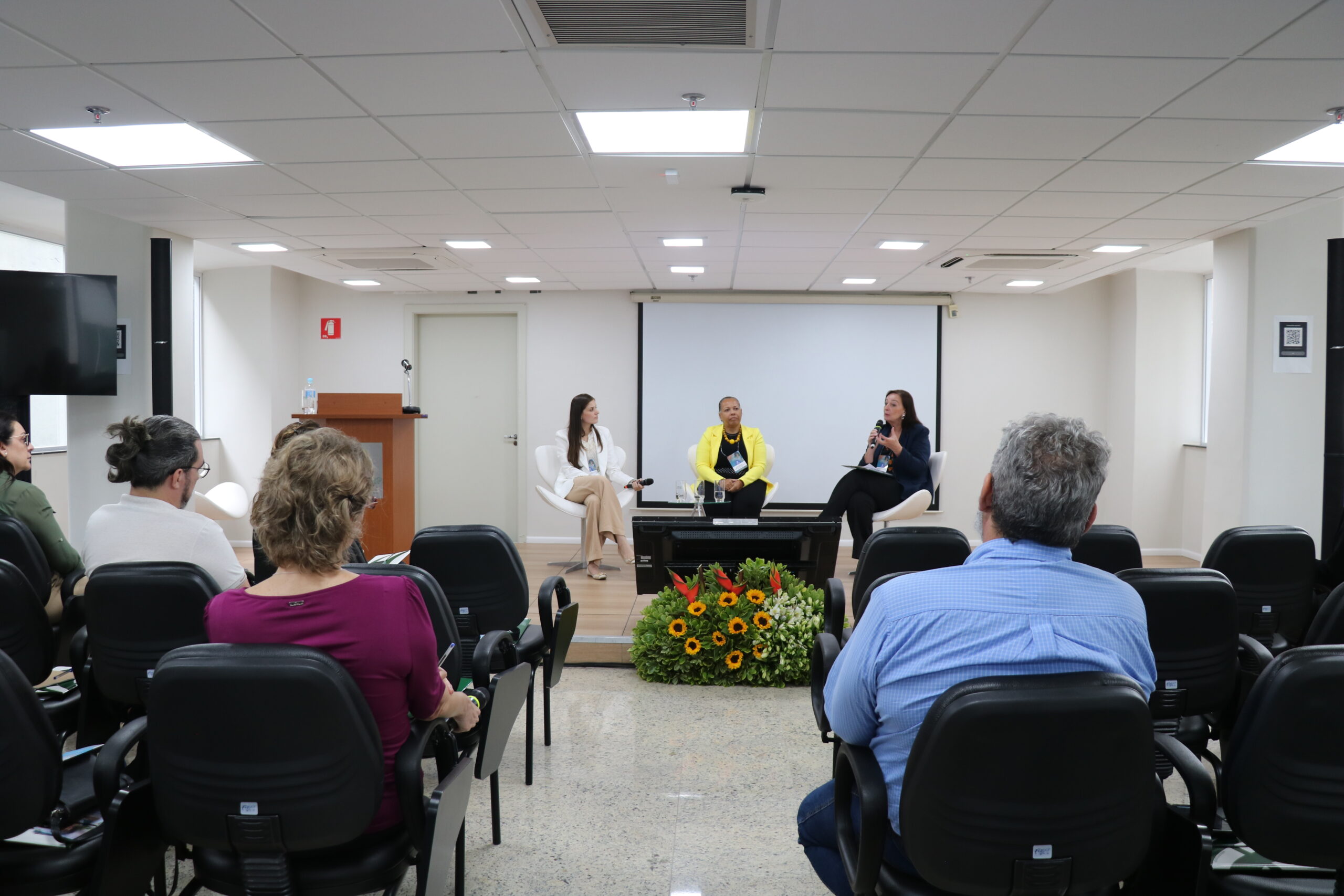 3 mulheres em uma mesa de discussão num auditório