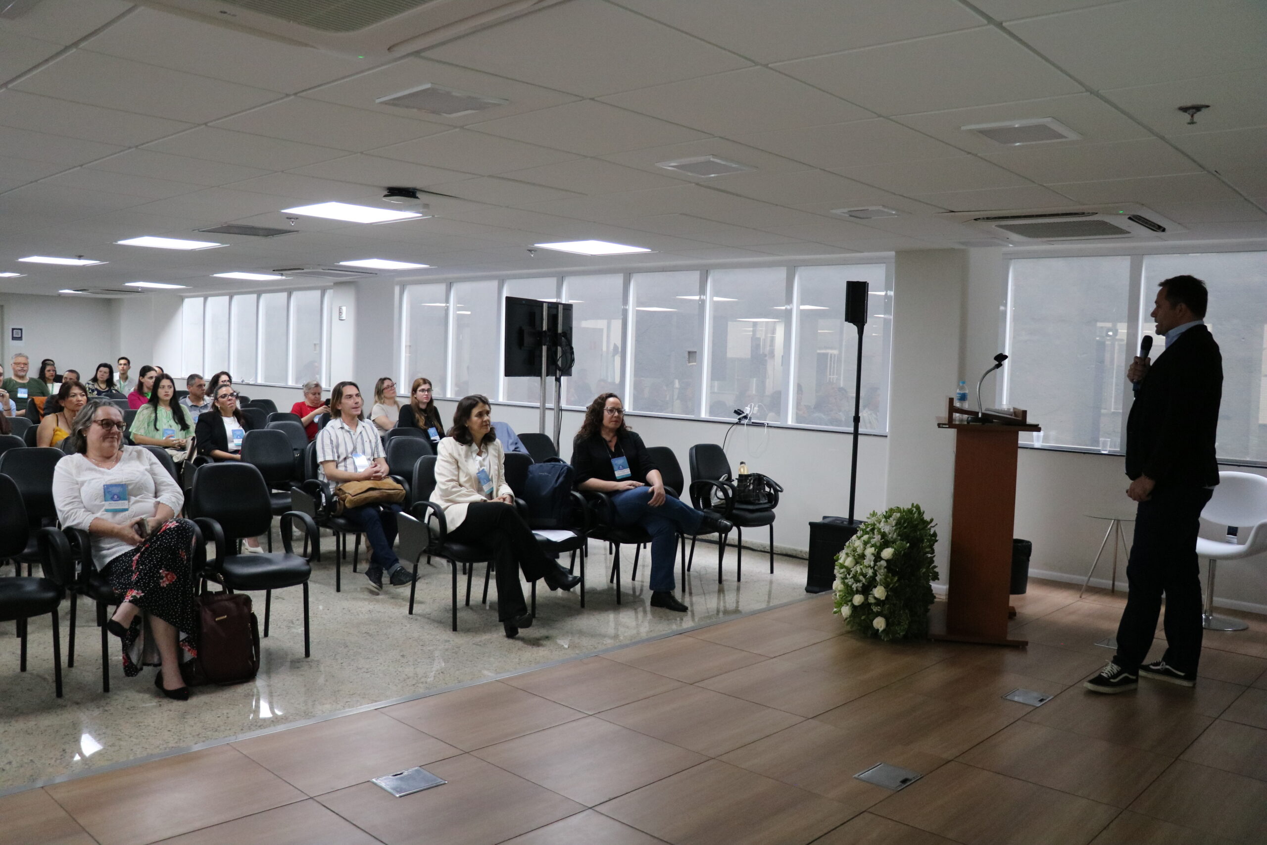 homem falando ao microfone frente ao público.