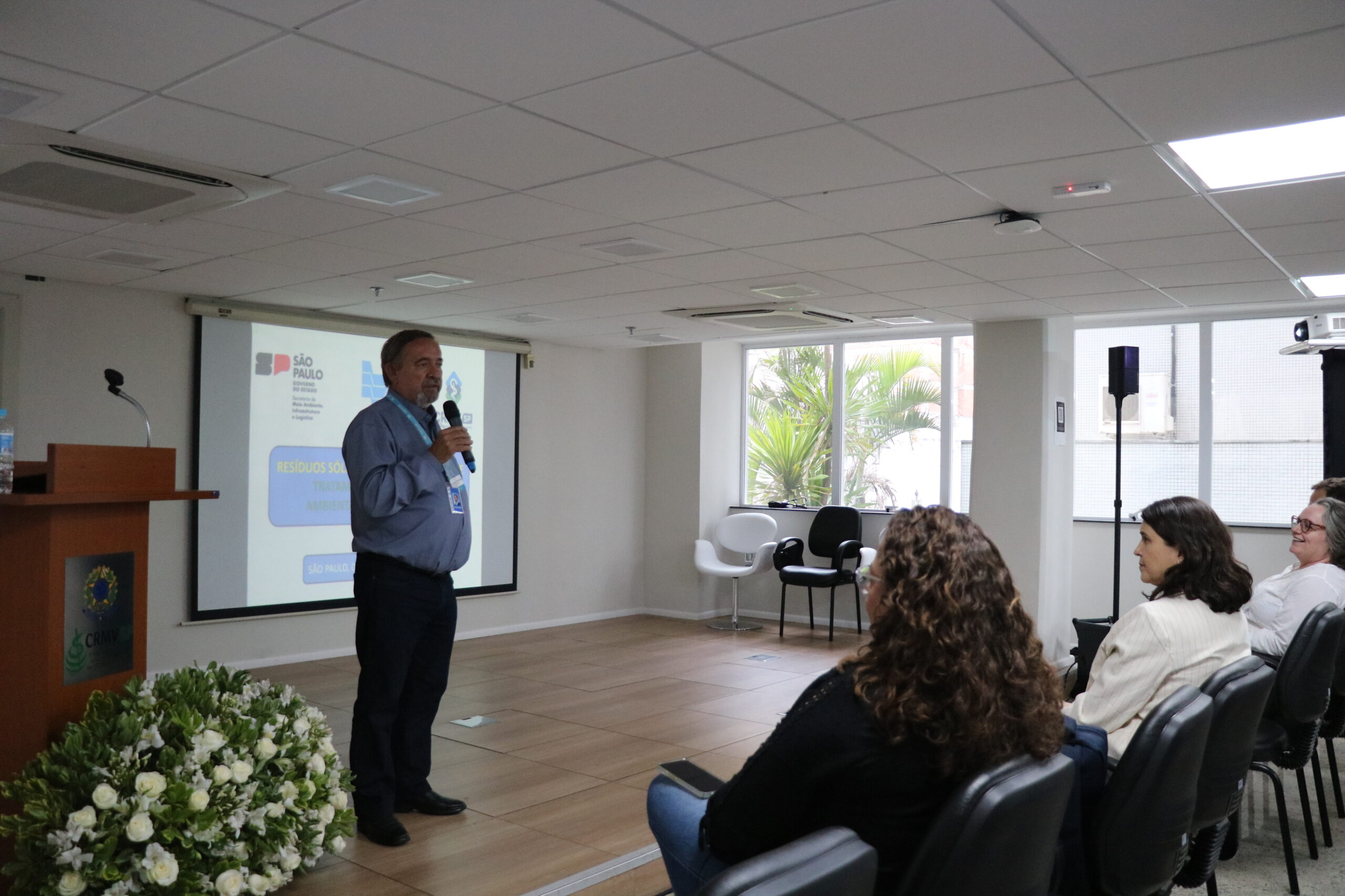 homem falando ao microfone frente ao público.