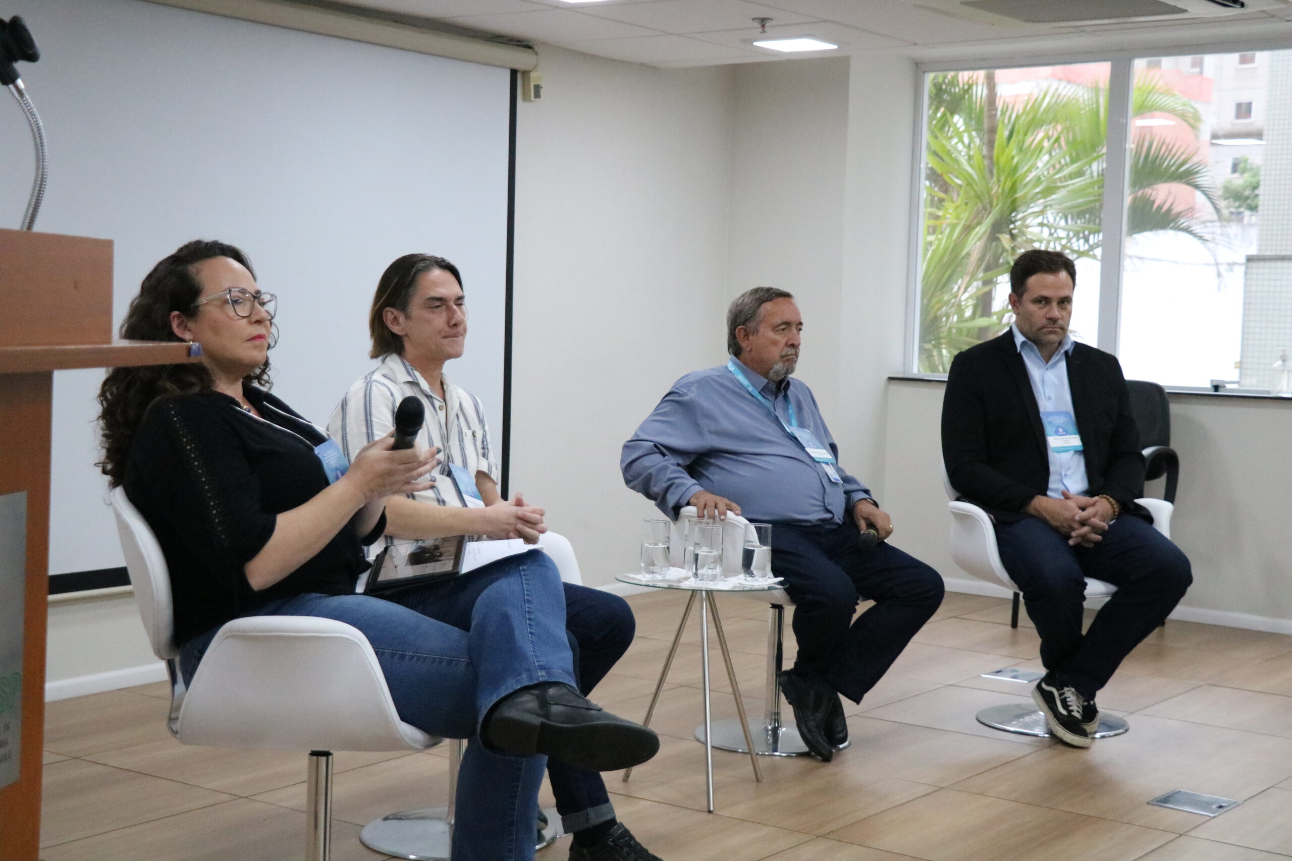 4 Pessoas sentadas em cadeiras para mesa redonda.