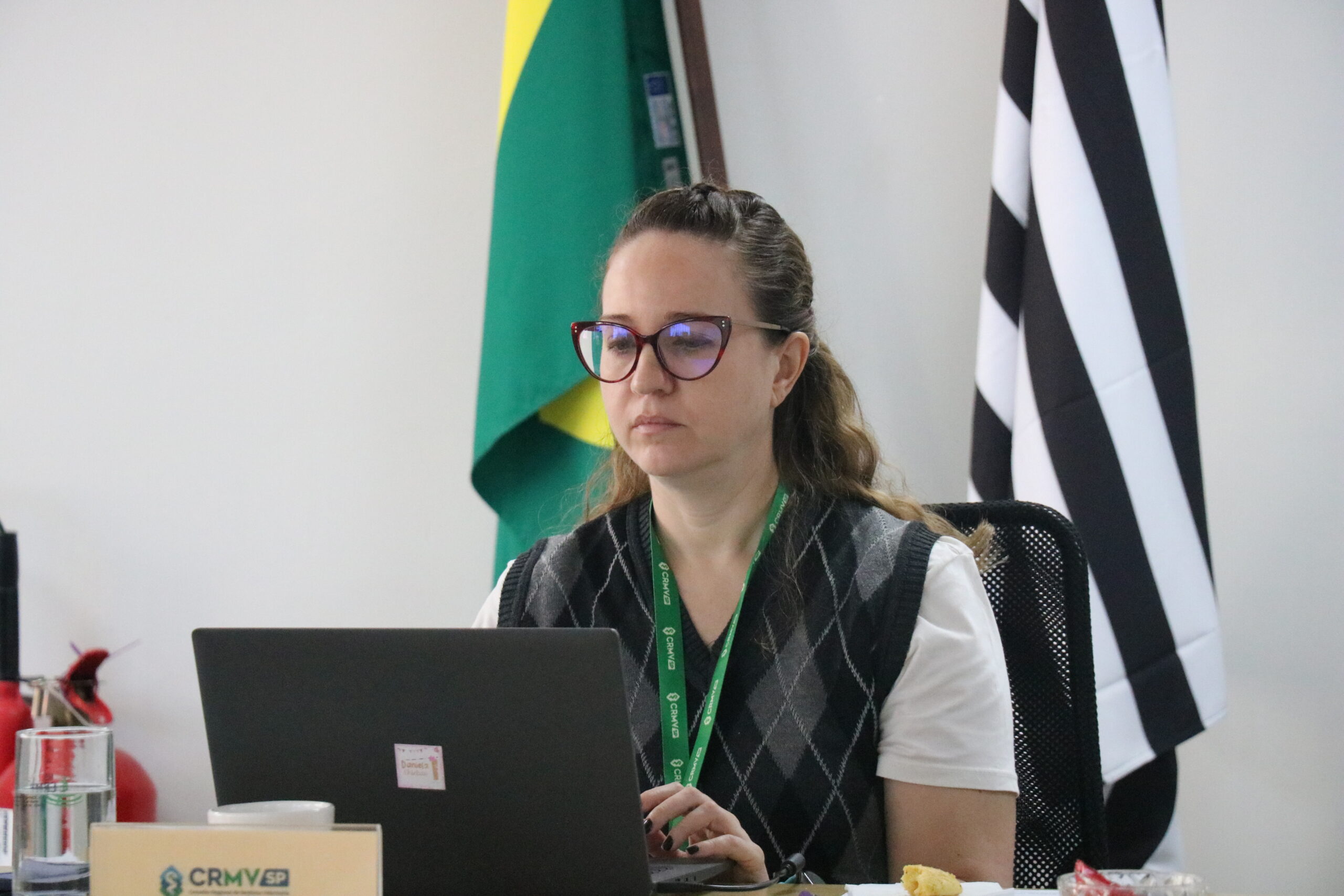Uma mulher durante reunião, olhando e digitando para um notebook.