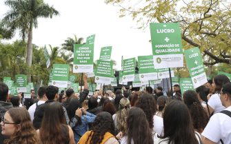Pessoas mobilizadas em caminhada pelas ruas da cidade, empunhando cartazes em defesa da graduação 100% presencial.