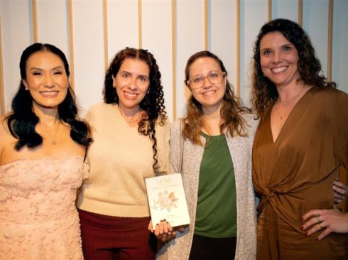imagem de quatro mulheres, uma segurando um livro.