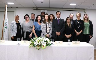 Homens e mulheres em pé pousando, com mesa à frente com arranjo de flores. Esses são os conselheiros e diretores do CRMV-SP para o triênio 2024-2027. Ao centro está a presidente do Regional.