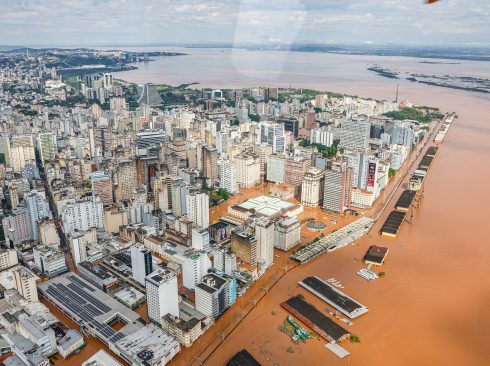 Sobrevoo mostra como a água barrenta tomou as ruas da cidade em meio a casas e prédios.