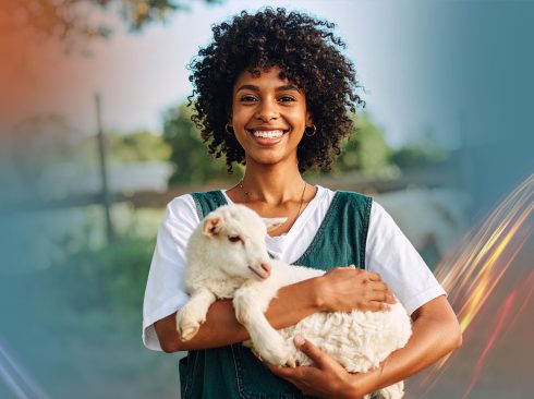 Imagem de divulgação nas cores azul e laranja, com a foto de uma jovem negra de cabelo crespo castanho escuro na altura dos ombros, usando blusa branca e macacão jeans, segurando um filhote de cabra no colo.