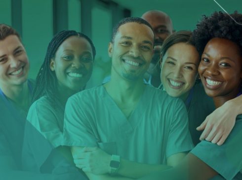 Seis pessoas, três homens e três mulheres jovens em pé abraçados e sorridentes usando uniforme verde comumente usado por médicos-veterinários clínicos.