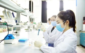 jovens mulheres de jaleco branco máscara trabalhando em um laboratório.