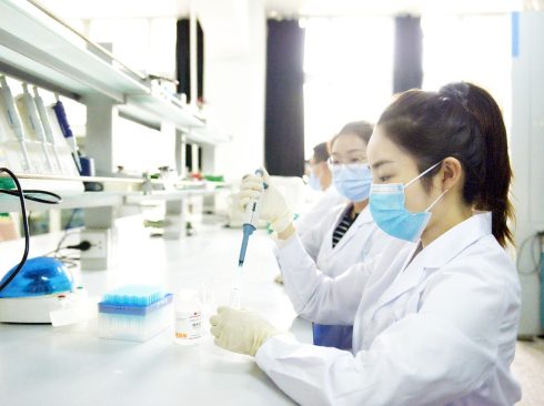 jovens mulheres de jaleco branco máscara trabalhando em um laboratório.