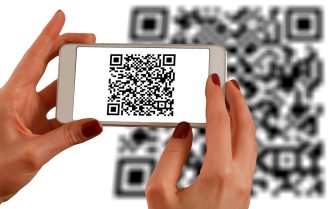 A imagem mostra uma mão que está segurando um celular, registrando um QR Code.