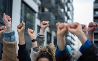 Várias mãos levantadas com o punho fechado dando a entender que as pessoas estão em uma manifestação.