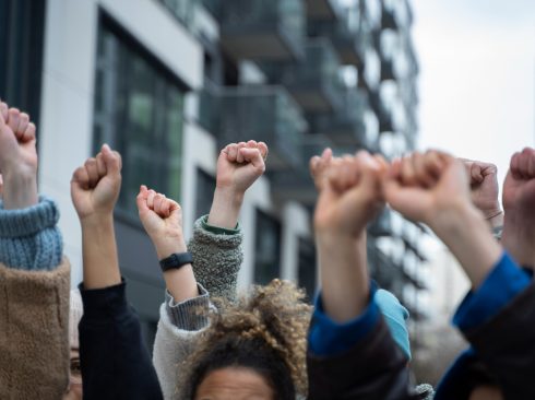 Várias mãos levantadas com o punho fechado dando a entender que as pessoas estão em uma manifestação.