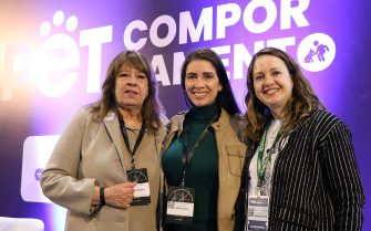 Três mulheres pousando para foto na frente de um painel roxo escrito Pet Comportamento em letras brancas. Da esquerda para a direita são elas: Deputada estadual Clarice Ganem, a vice-presidente do CRMV-SP Carolina Saraiva de Filippos e a presidente do CRMV-SP, Daniela Pontes Chiebao.