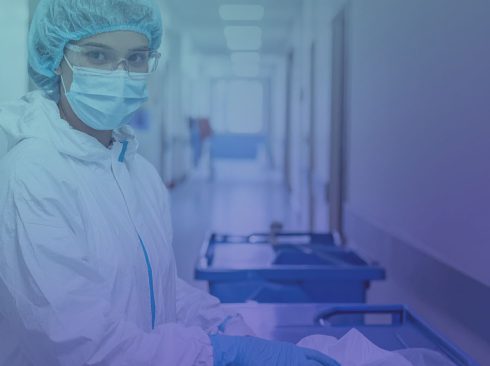Mulher usando jaleco branco e mascara n95 e óculos de proteção em laboratório.