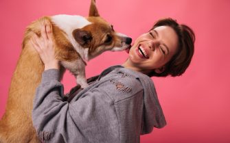 mulher sorridente de casaco brincando com o cachorro.