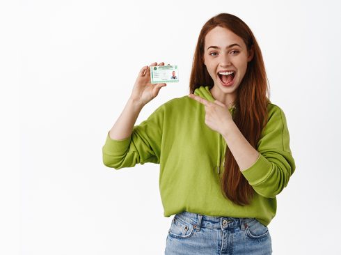 A imagem mostra uma moça sorrindo e apontando para a cédula de identidade profissional.