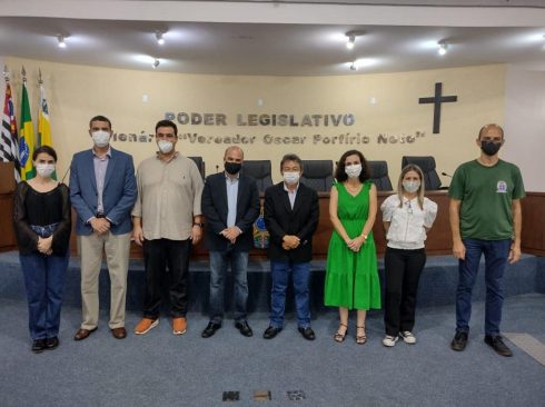 Oito pessoas estão de pé posando para a foto. Todos de máscara e posicionados em frente a tribuna do Plenário da Câmara Municipal de Paraguaçu Paulista. Na foto o prefeito da cidade, os médicos-veterinários do serviço municipal, e o vice-presidente e o coordenador técnico médico-veterinário do CRMV-SP.