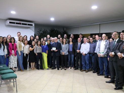 Foto mostra mais de 40 profissionais de Sorocaba reunidos com os representantes do CRMV-SP. Estão todos de pé, posados lado a lado e sorrindo para a câmera. O presidente está ao centro com a placa de homenagem da Amvip nas mãos.