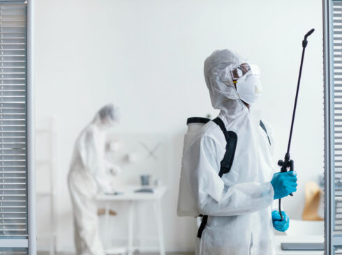 Imagem mostra equipe fazendo limpeza e dedetização. São dois homens, eles usam EPIs como luva, máscara e roupa de proteção.