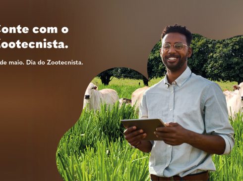 A imagem traz um homem negro de óculos sorrindo, com um tablet na mão em frente a uma imagem recortada de um pasto bem verde com bois da raça nelore ao fundo. No canto esquerdo, em fundo marrom há os seguintes dizeres em branco: Conte com o Zootecnista. 13 de maio. Dia do Zootecnista.