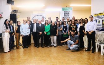 Profissionais da Zona Norte posam na foto com a diretoria do CRMV-SP. O grupo com 30 pessoas está de pé e sorri para a foto. Somente um profissional está agachado. Ao fundo, banner da Sociedade dos Médicos-veterinários da Zona Norte de São Paulo e do CRMV-SP com os dizeres: Bem-vindo ao nosso evento).