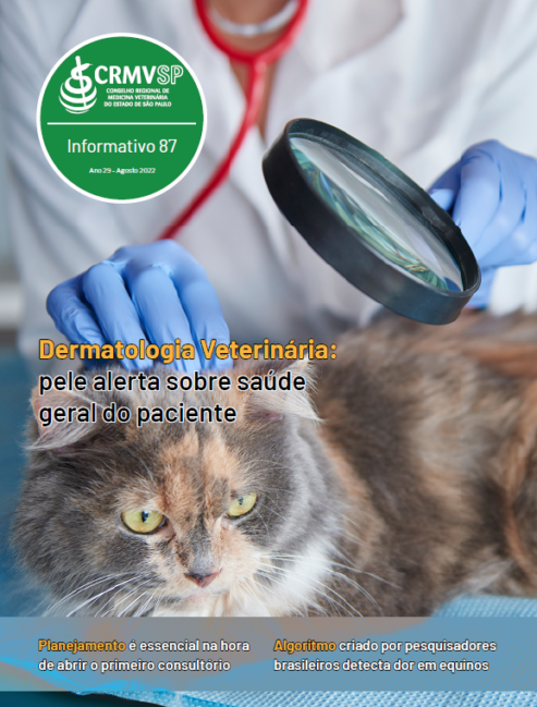 Capa do informativo 87 traz um médico-veterinário com uma lupa examinando um gato rajado.