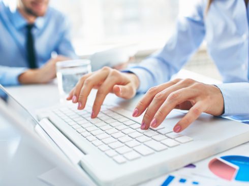 mãos femioninas digitando em um teclado branco de notebook.