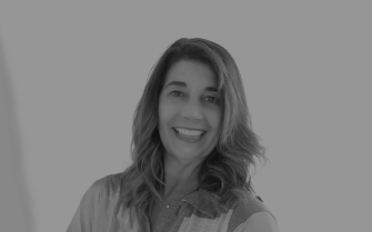 Foto em preto e branco da zootecnista Mônica Junqueira. Na foto ela aparece sorrindo, veste um camisa, usa um colar com ponto de luz e cabelos louros e na altura dos ombros.