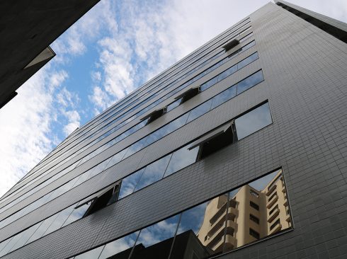 A imagem mostra a vista lateral nova do prédio, com janelas espelhadas e superfície em pastilha de cor verde.