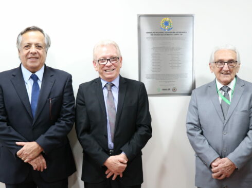 A foto mostra os três presidentes do CRMV-SP, da atual gestão e das gestões anteriores, ao lado da placa do CRMV-SP.