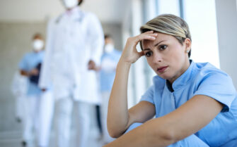 Enfermeira perturbada sentada em um corredor pensando em algo