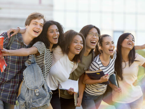 Picture of multiethnic group of young happy students standing outdoors. Looking aside.