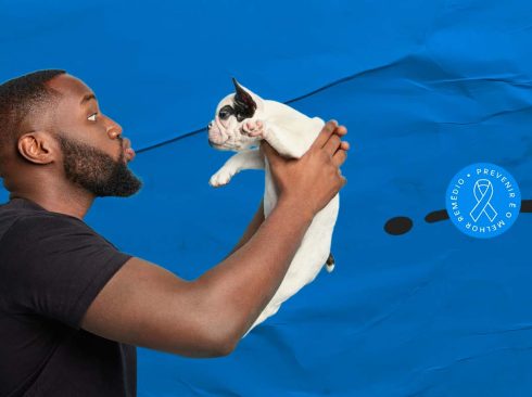 imagem de um homem negro, segurando um gato branco.