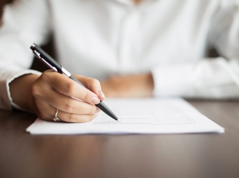 mão feminina assinando documento.